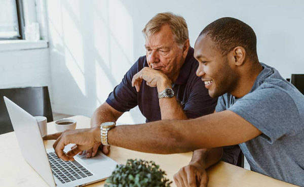 a young person helping an adult with his computer
