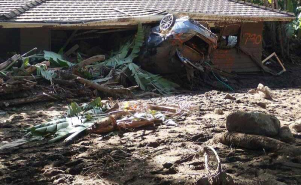 A car and a house on top of each other covered with mud