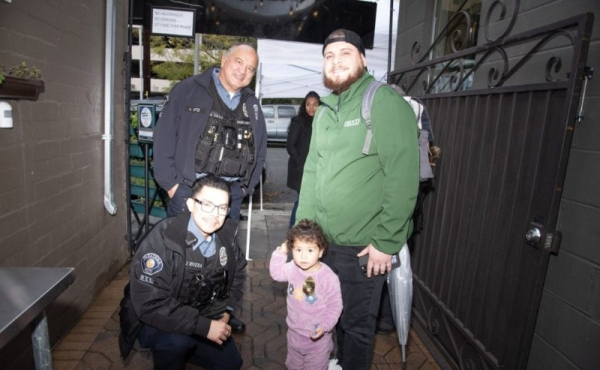 Two police officers smiling with a man and a child