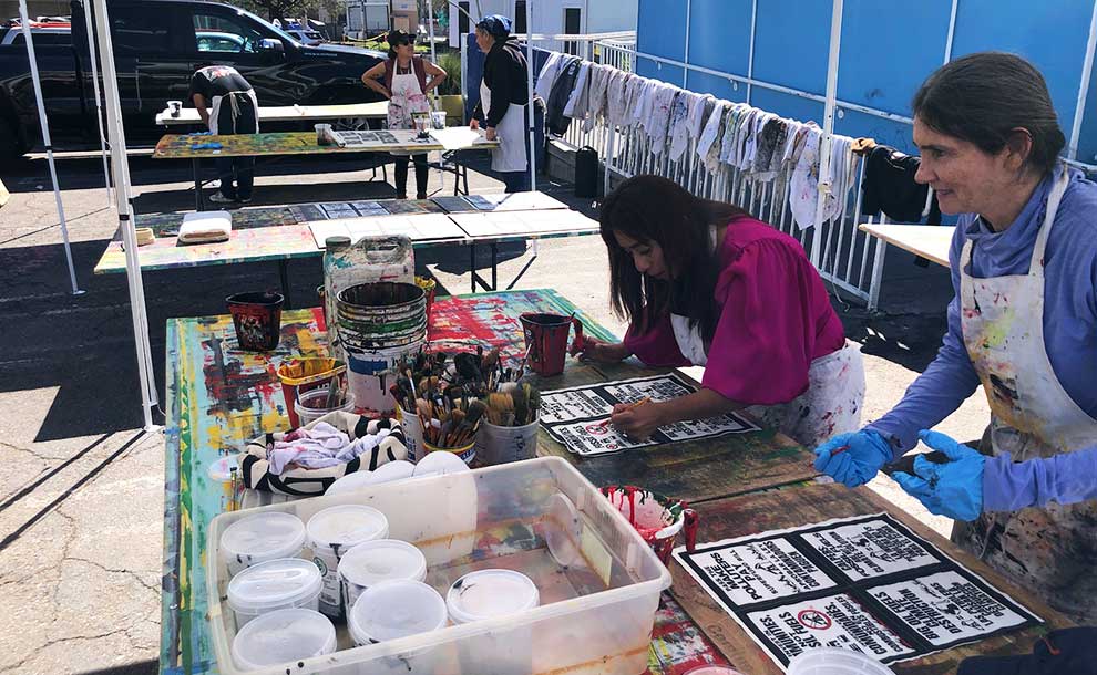 women painting with ash from fire