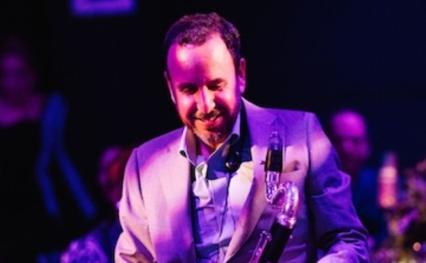 A man smiling and holding a clarinet