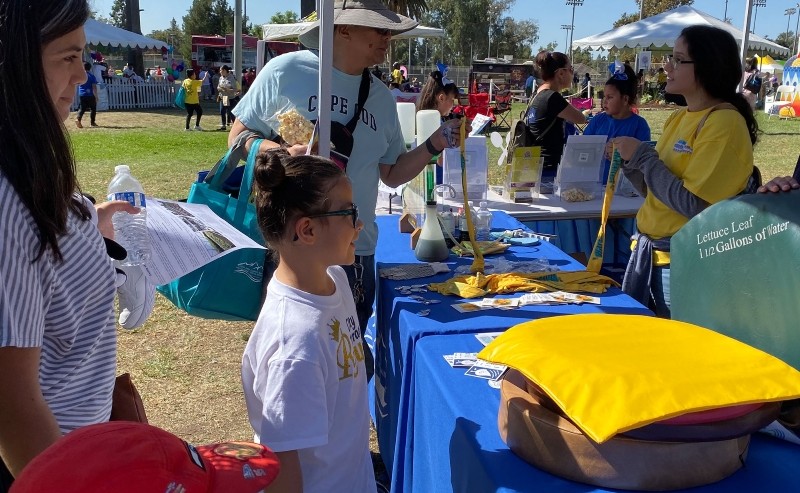 A girl standing in front of a booth learning about water conservation