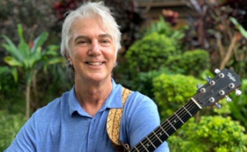 A man smiling with a guitar
