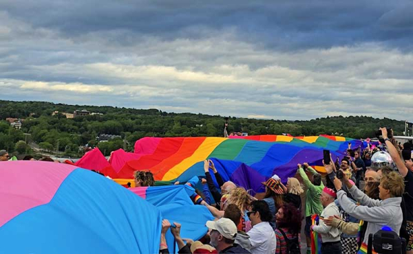 people holding a flag over a bridge