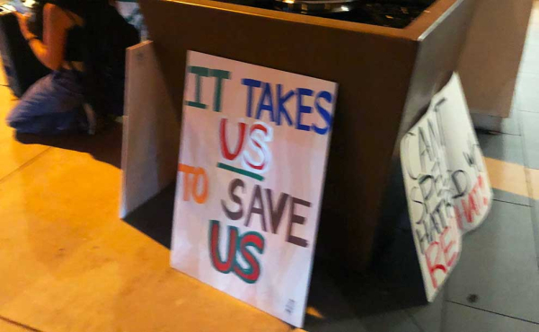 a sign that says: It takes US to save US
