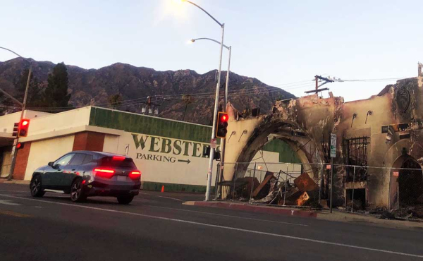 a car stopped by a light on a street with a burned structure