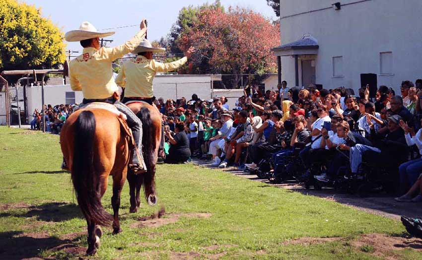 men on horses perform to students
