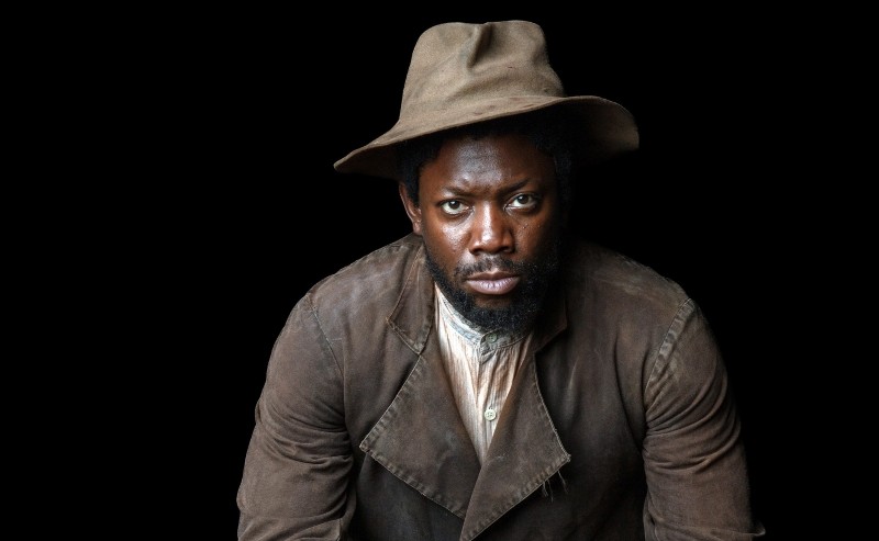 A man in a brown jacket and hat