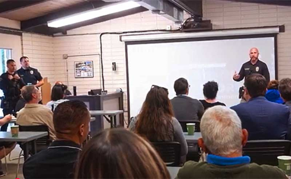 An officer speaking to a group of poeple
