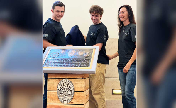 a woman and two sons by a plaque commemorating her late husband