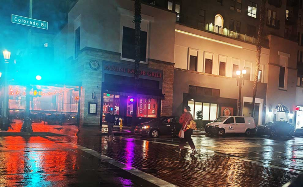 a man crossing a street on a rainy night