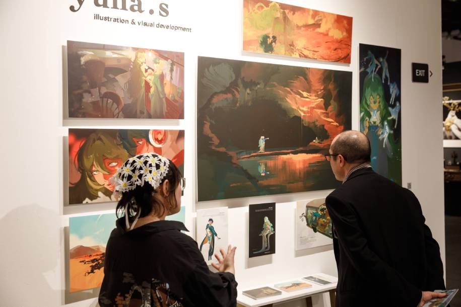 A graduate art student discusses her work with an attendee to Spring show.