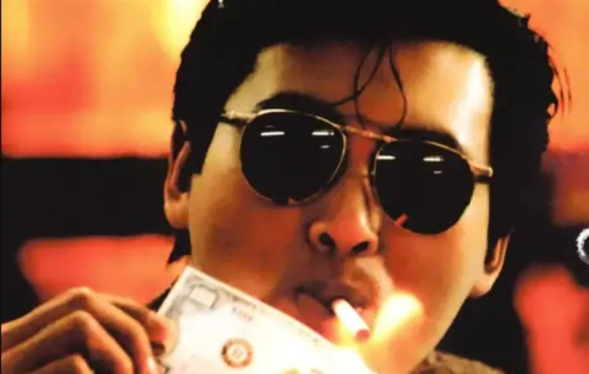 Cool man with glasses lights a cigarette off a roll of burning cash