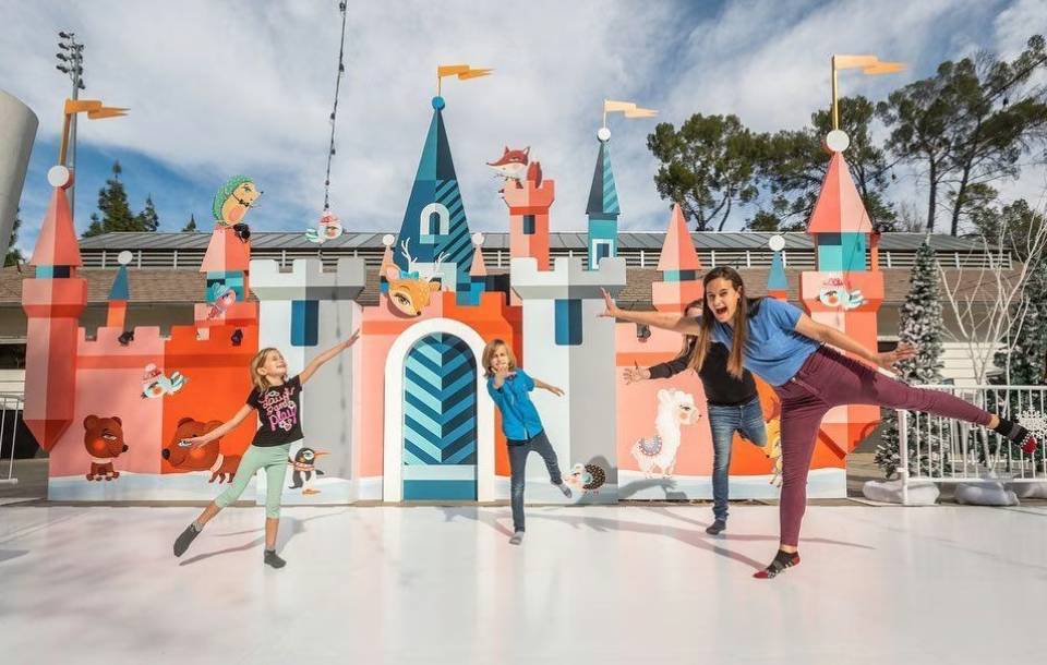 children pose in front of large play castle