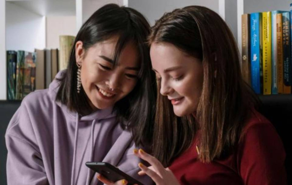 Two teens chat over a cell phone