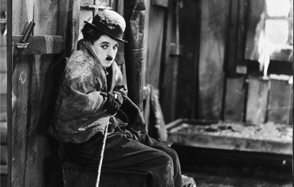 Mustached Little Tramp character shivers inside a log cabin