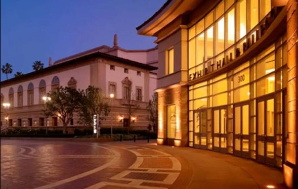 late evening purple sky looms above the lighted entrance to crescent shaped entrance of Exhibit Hall with golden lights