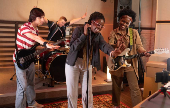 two men and one woman play instruments while a lead female vocalist laughs
