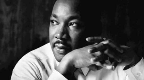 close-up black and white portrait of Dr. King with hands folded and gazing off-camera
