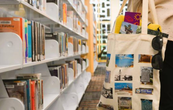 close-up of a decorated book bag hanging from an arm in a row of library shelves