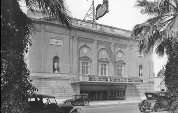 1920s three story theater building exterior view with sign above and Model T cars on street