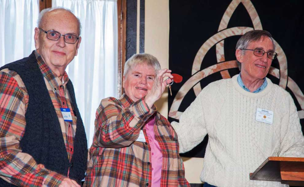 a woman holding a key in her hand while two men ar smiling