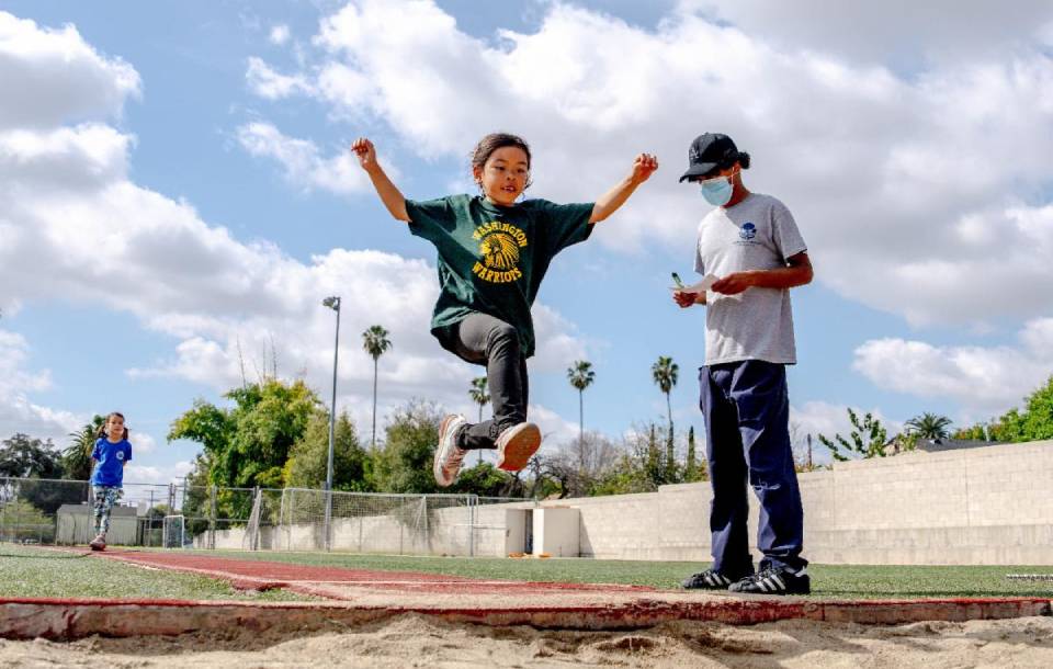 an elementary student leaps for a measured jump at a track