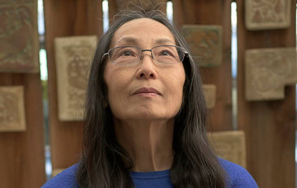 woman in glasses gazing up with tile squares hanging behind her